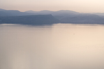 Fototapeta premium Misty morning on the Sea of Galilee, with Mount Arbel seen through fog in the distance