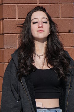 Girl against wall eyes closed in sun