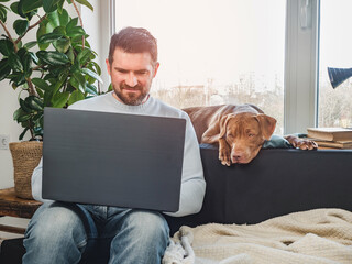 Handsome man and a charming puppy. Close-up, indoors. Studio photo, white color. Concept of care, education, obedience training and raising pets