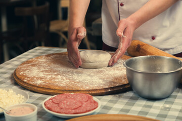 Cooking pizza in a cafe. The chef prepares pizza dough for baking in the oven.
