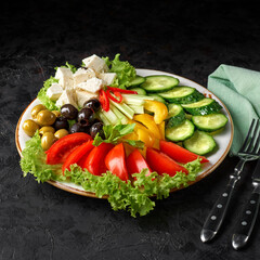 Assorted fresh vegetables in a plate on a black background. appetizer or snack.