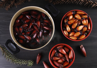 Typical araucaria seeds used as a condiment in Brazilian cuisine in winter. Brazilian pinion nuts in brown and red wooden bowl on gray wooden background
