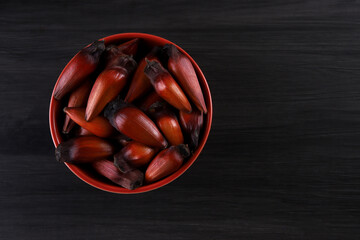 Typical araucaria seeds used as a condiment in Brazilian cuisine in winter. Brazilian pinion nuts in brown and red wooden bowl on gray wooden background