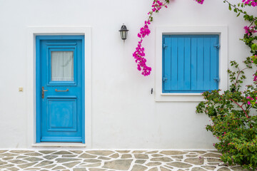 Greek house with blue doors and decorated with bougainvillea flowers on Antiparos island. Cyclades, Greece - obrazy, fototapety, plakaty