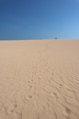 Footsteps on a beige sand dune in Taroa la guajira colombia with a blue sky, walking in the heat in a dry and sunny day in the desert 