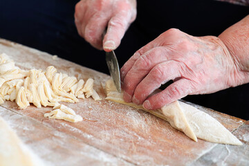 Closeup of a seniors hands cutting egg noodles