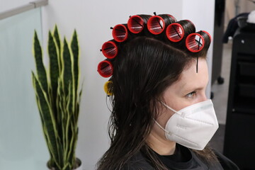 Young woman with hair curlers in brown hair, volume winder