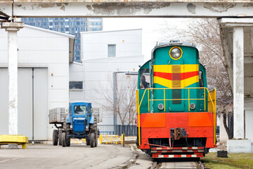 Old, but in working order, diesel locomotive tractor and wheeled tractor leave the depot.