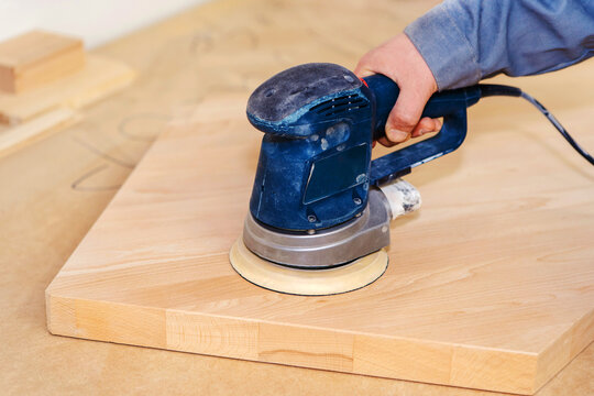 The process of processing a board with an eccentric sander. Furniture production in a carpentry workshop. Close-up