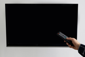 Hand Pointing Remote Control At Empty TV Screen At Home