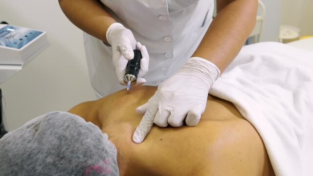 a cosmetologist gives an injection in the patient's back during the procedure