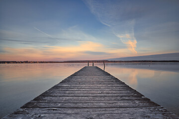 Fototapeta na wymiar Early sunrise with clouds and pier on the lake