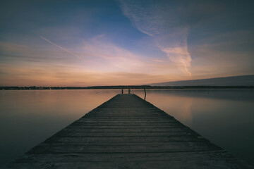 Early sunrise with clouds and pier on the lake
