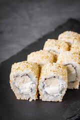 appetizing sushi roll with Philadelphia tofu sesame cheese on a black stone plate