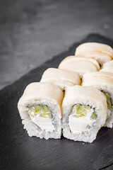 appetizing sushi roll with philadelphia cucumber cheese and escolar on a black stone plate
