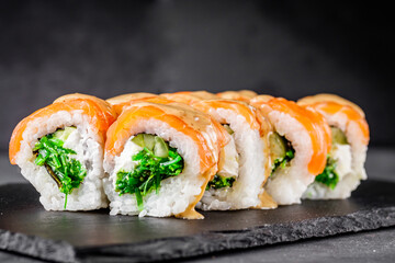 appetizing sushi roll philadelphia with salmon cucumber and chuka on a black stone plate
