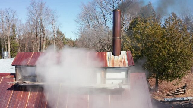 Sugar Shack in Quebec Boiling Sap From Maple Trees to Produce Maple Syrup in Wooden Cabin. Billowing Smoke Coming From Chimney 4k Aerial Drone Shot