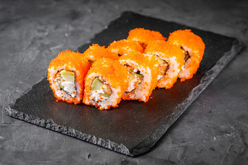 appetizing sushi roll california with eel cheese cucumber avocado and caviar masago on a black...