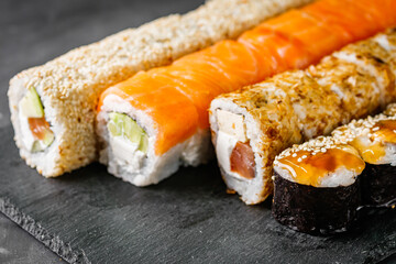 appetizing set of sushi roll on a black stone plate