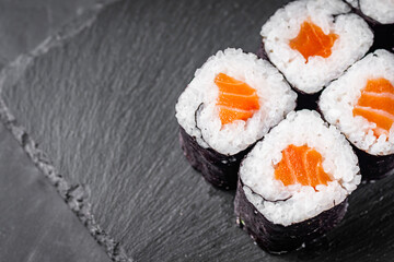 appetizing sushi roll maki with salmon on a black stone plate