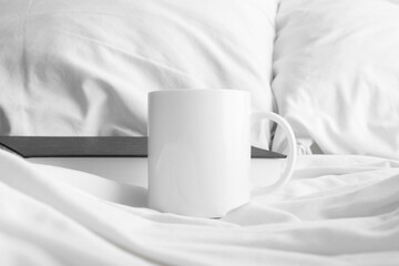 Fototapeta na wymiar White mug mockup with a book on the bed.