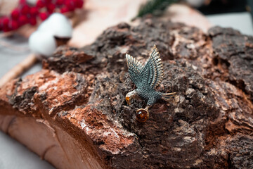 Decoration in the form of a flying eagle of bronze and amber on a wooden background
