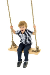 Cute boy sitting on rope swing. Photo session in the studio
