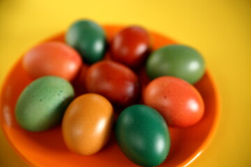 Fototapeta na wymiar Colorful easter eggs close up on orange plate yellow background