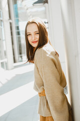 Portrait of a young girl. A brunette in a yellow sweater smiles and looks into the camera