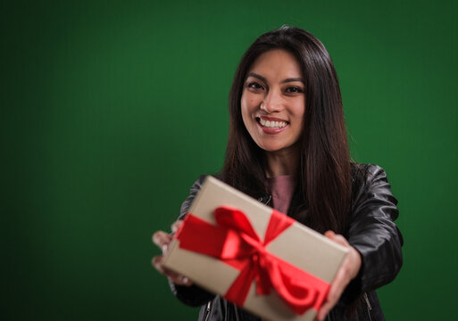Young woman holds a gift box towards the camera - studio photography - Powered by Adobe