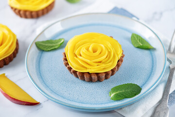 Chocolate tartlets with chocolate cream filling and mango fruit in the form of roses