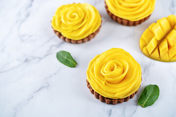 Chocolate tartlets with chocolate cream filling and mango fruit in the form of roses