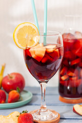 
Vista de un vaso y una botella de sangría con un plato de frutas en formato vertical