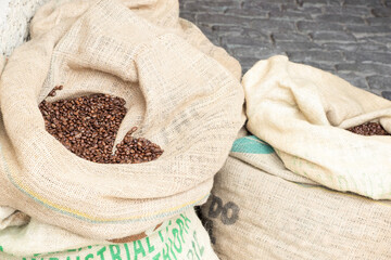Coffee beans are lie in big jute sacks, ready for selling. Dark roasted selected beans for good beverage.