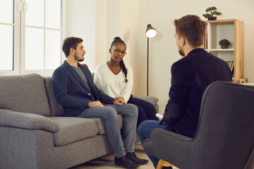 Young couple looking for solution to family problem and asking professional psychologist for help. Multicultural boyfriend and girlfriend meeting with therapist and discussing relationship issues - Powered by Adobe