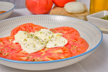 Close up tomato and mozzarella salad on a white wooden table