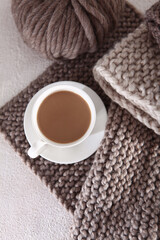 Cup of coffee and knitting in brown tones. Knitting needles. Hobby concept. Yarn for hand knitting. Top view. Light background.Vertical photo.