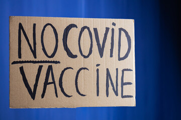 Vaccination protest concept. 'No covid vaccine' protestive placard. Anti vaccination placard on a blue background