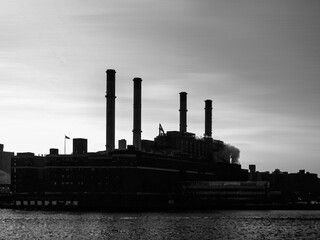 Silhouettes of four smokestacks on gray sky as background