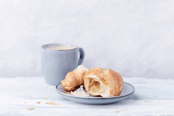 Croissant with coffee on bright wooden background. Close up. Copy space.