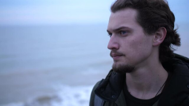 Portrait of young depressed male lonely walks on a winter beach break. 