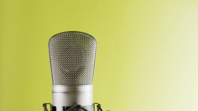 Studio microphone on an anti vibration stand, rotating. Professional audio recording equipment on yellow to white background