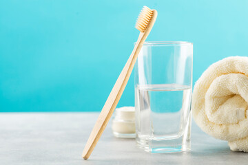 A bamboo toothbrush, a glass of water, a white cotton towel and toothbrush powder in a jar. Biodegradable personal care products. No plastic concept