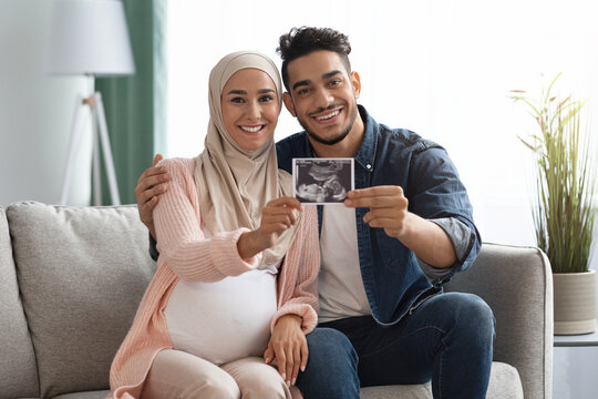 Pregnant Islamic Lady And Her Husband Showing Baby Sonogram Picture At Camera