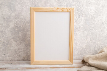 White wooden frame mockup with linen textile on gray concrete background. Blank, vertical orientation, still life.