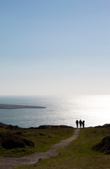 Wales, remote dramatic Bardsey island. Isolated remote landscape with foreground of green fields and the calm sea with sun glinting, in the distance. Medieval pilgrimage destination.  Copy space.