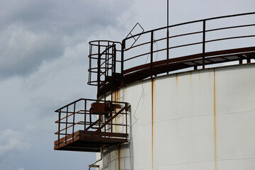 huge industrial tank with a metal ladder against the blue sky