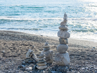 Pyramid of pebbles and stones on beach. Sunny day at seaside. Leisure on ocean coast.