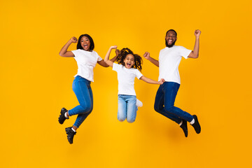 Fototapeta na wymiar Portrait of emotional black family jumping at studio