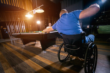 Adult men with disabilities in a wheelchair play billiards in the club